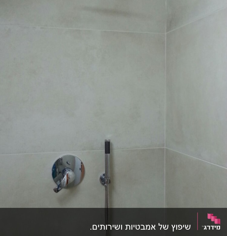 ראש מקלחת עגול וברז חדש על קיר אריחים